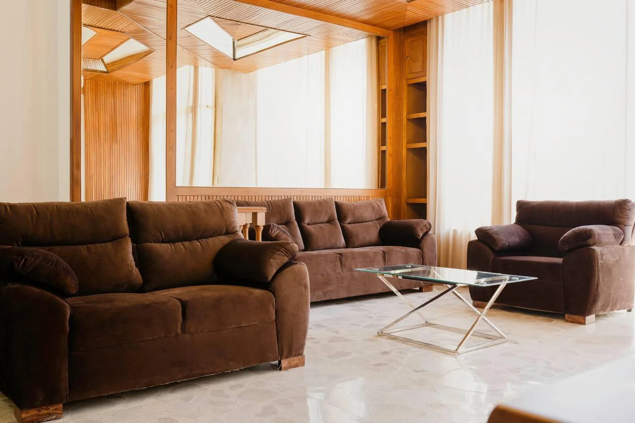 Sala de estar con sofás, mesa de cristal, espejos y plafón de madera